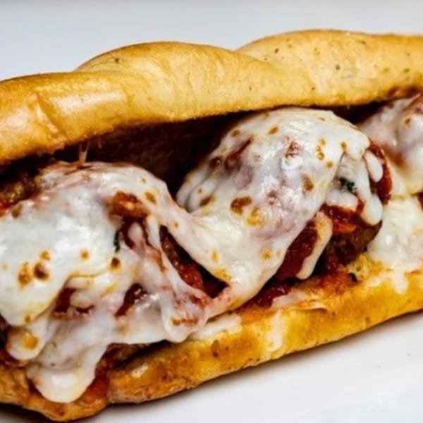 A By the Bucket meatball sub, overflowing with melted mozzarella cheese and rich red sauce.