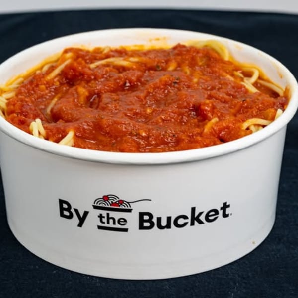 Spaghetti with red marinara sauce in a white By the Bucket container.