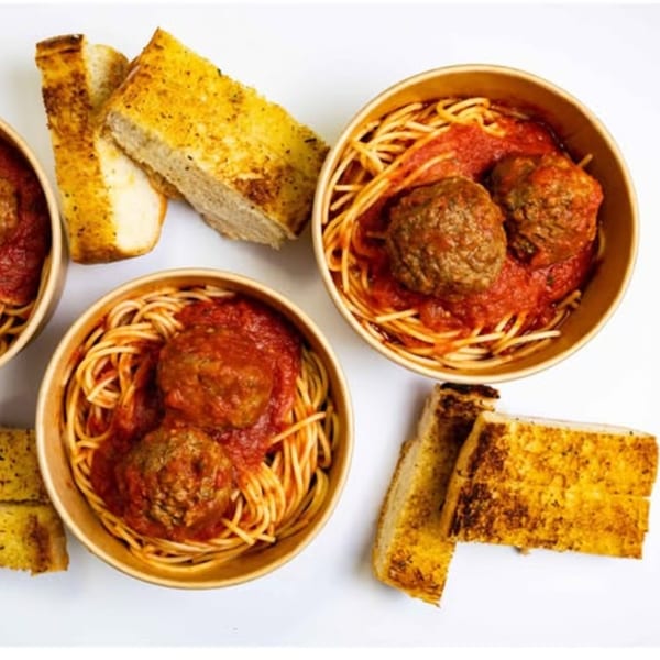 Two buckets of spaghetti and meatballs with tomato sauce, served with garlic bread.